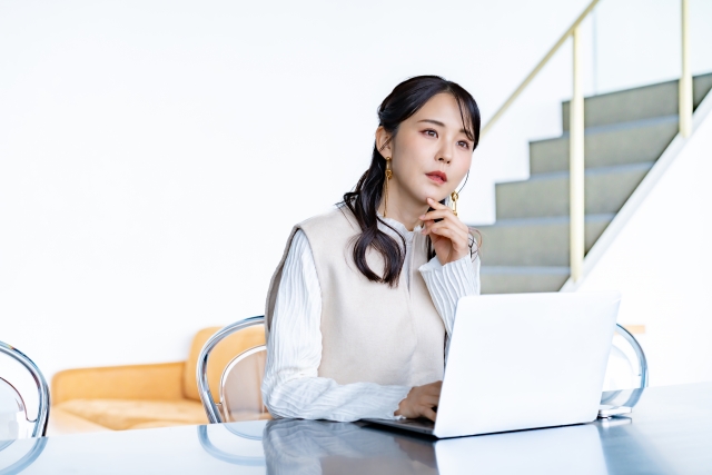 パソコンを見て考える女性の画像